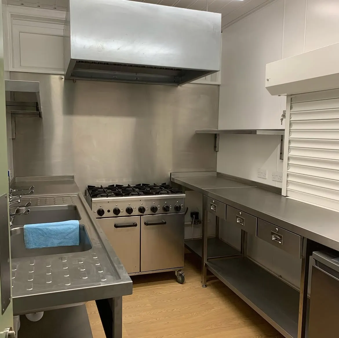 Completed commercial kitchen with stainless counters, extraction canopy and socket outlets
