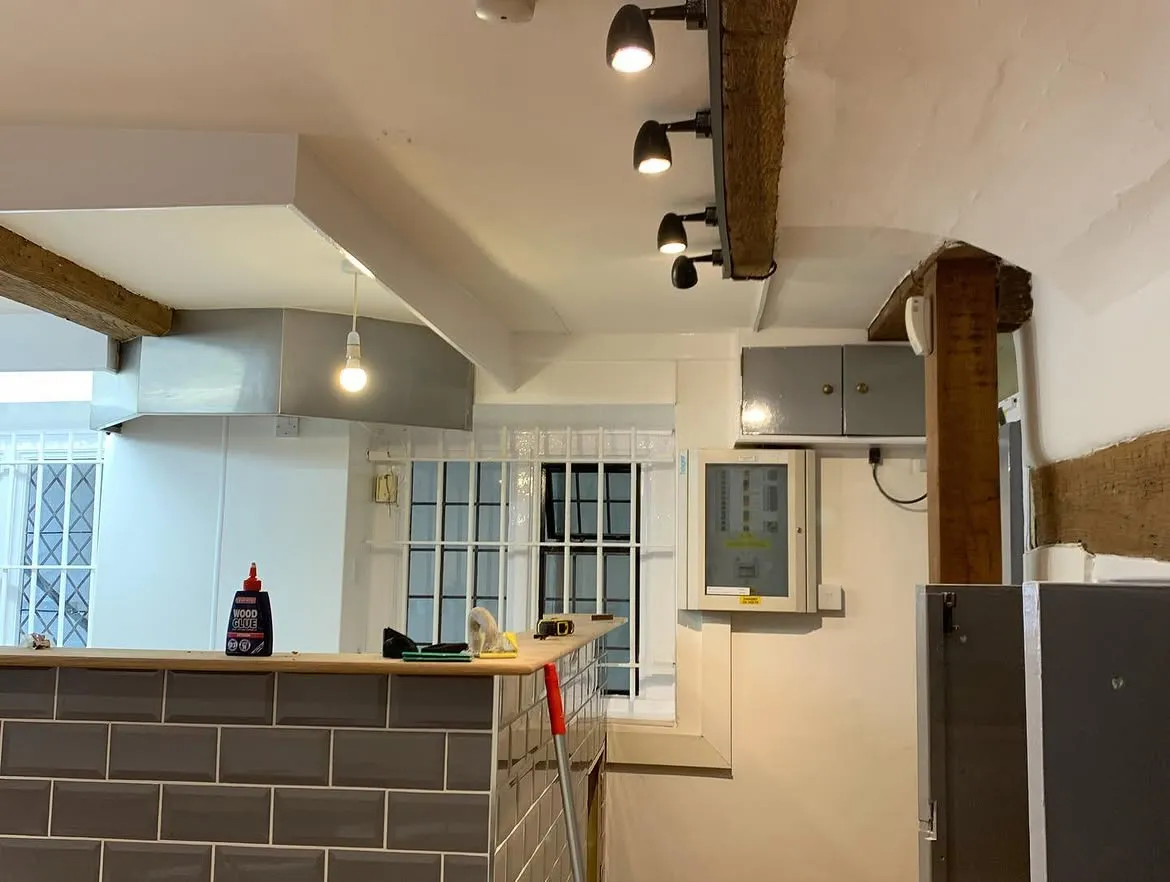 Track spotlights mounted on an exposed beam in a Grade I listed building on Guildford High Street