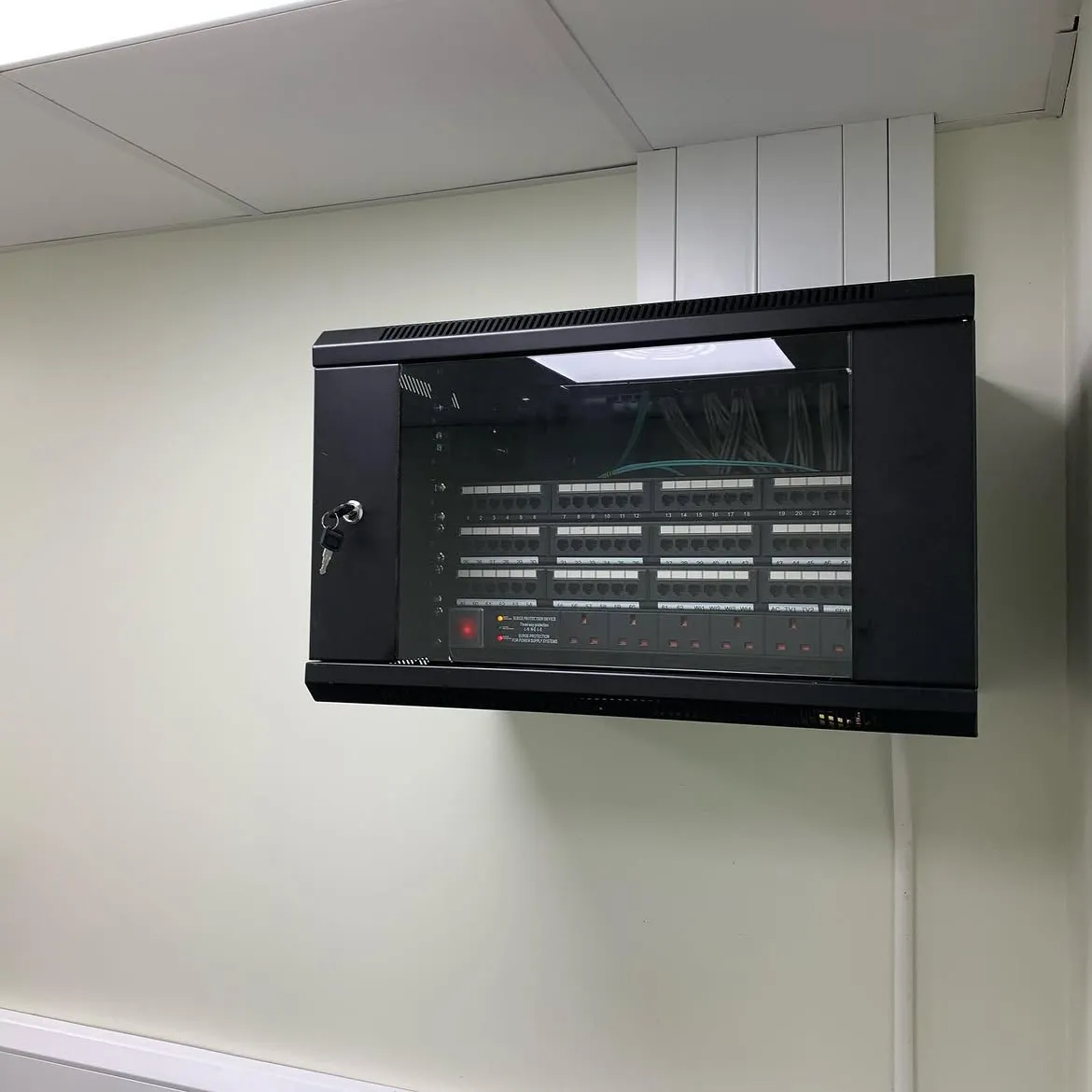 Wall mounted data cabinet with patch panels and surge protection, installed with fibre links